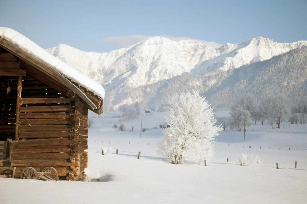 Verschneite Holzhütte vor winterlicher Berglandschaft
